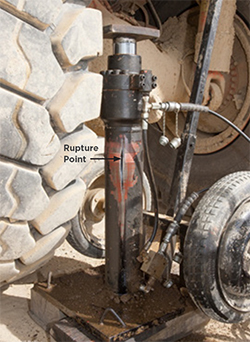[image] Hydraulic ram with a rupture in the barrel and the edge of a truck tyre to the side