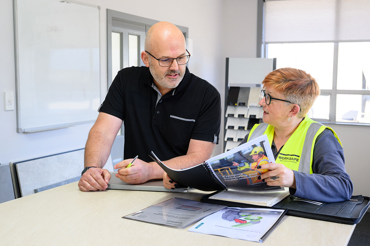 [image] Inspector with worker referring to some WorkSafe guidance