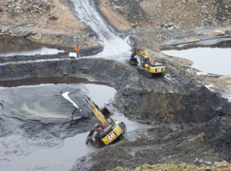 [image] Excavator tipping sideways into pond, with second excavator sitting on bank above
