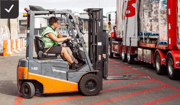 [image] photo of a worker driving an electric forklift outside near a large truck