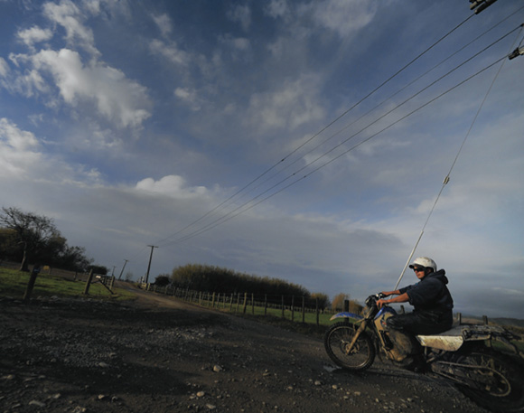 [image] Farmer wearing a helmet, riding a two-wheeled bike on an unsealed road