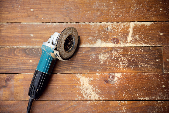 [image] Electric grinder placed on wooden planks with wood dust spread around. 