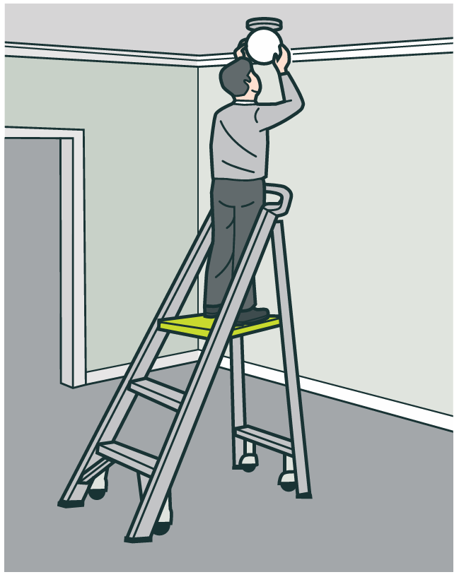 A worker using a step platform to change an overhead bulb.